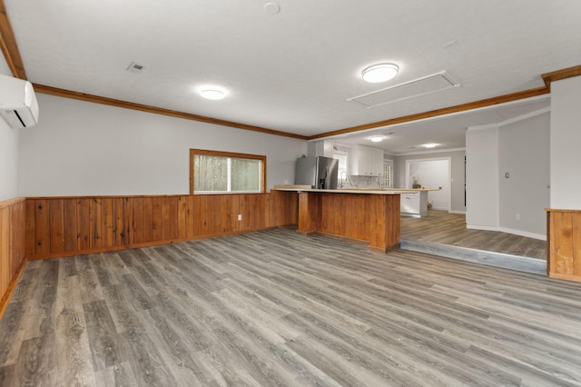 kitchen featuring a wall mounted air conditioner, stainless steel fridge with ice dispenser, light hardwood / wood-style flooring, kitchen peninsula, and ornamental molding