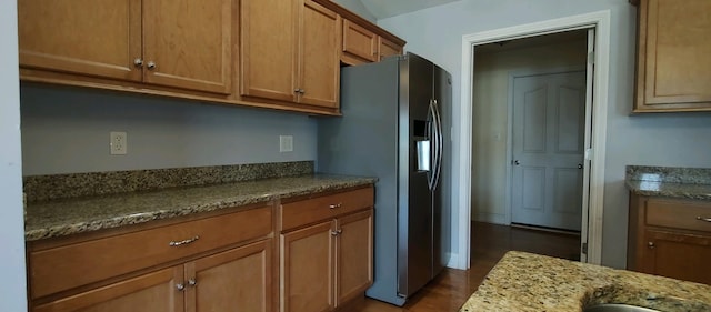 kitchen with hardwood / wood-style floors, stainless steel fridge, and light stone countertops