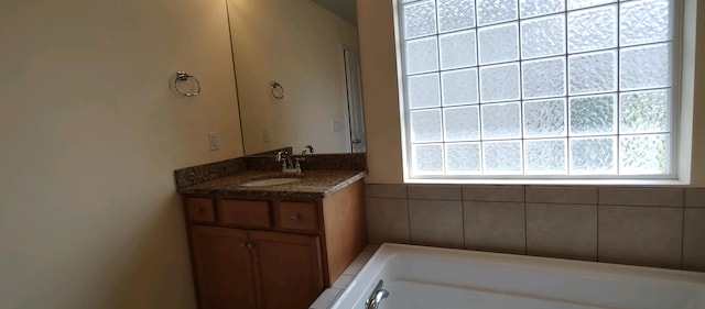 bathroom with a wealth of natural light, a washtub, and vanity