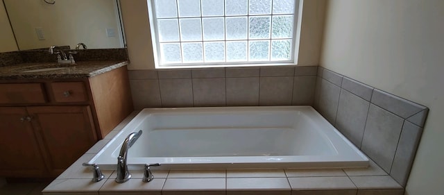 bathroom featuring tiled bath and vanity