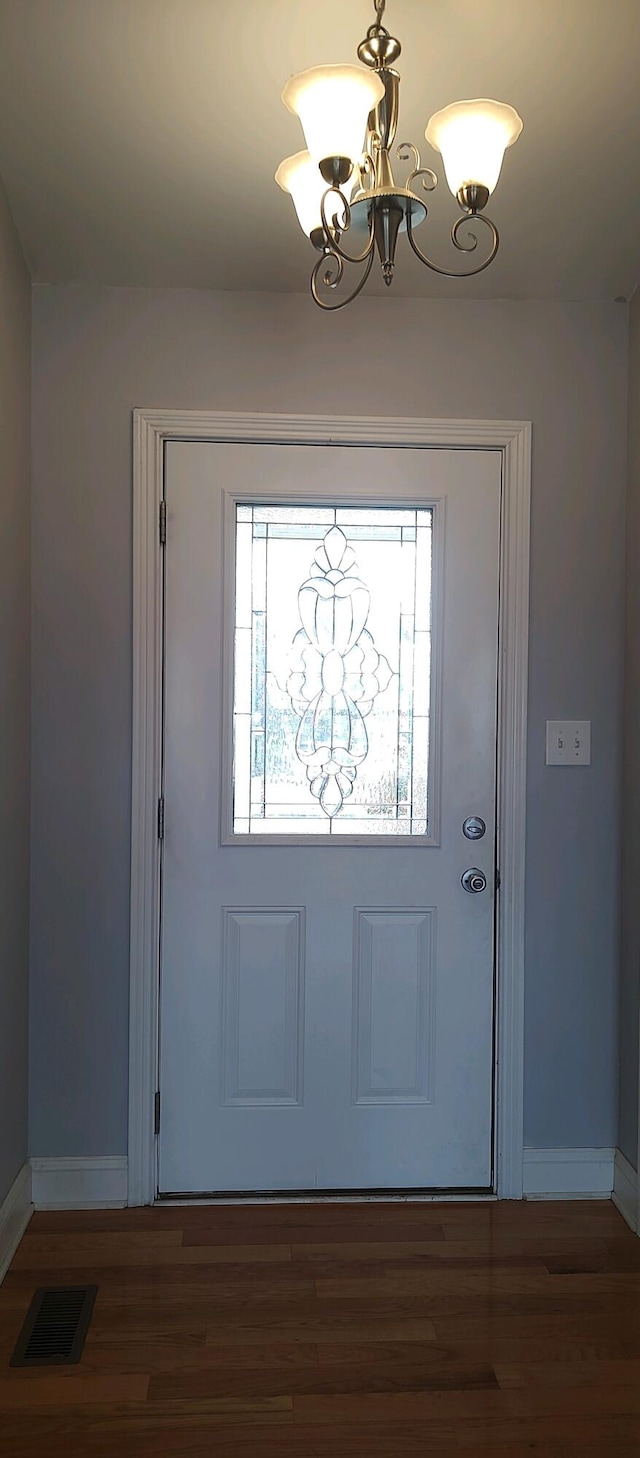 foyer entrance with dark wood-type flooring and a chandelier