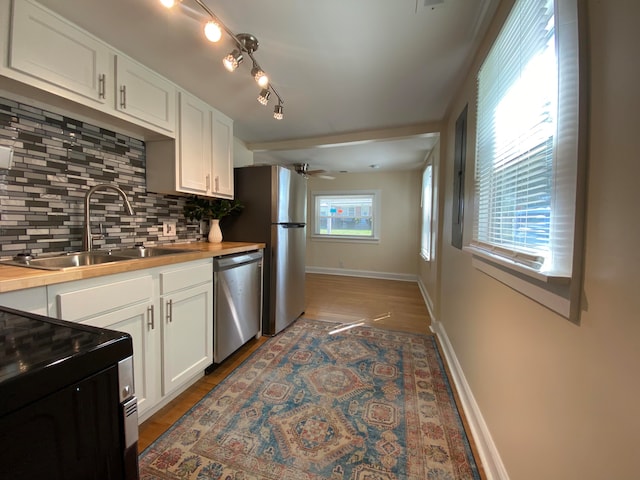 kitchen featuring white cabinetry, decorative backsplash, a wealth of natural light, and dishwasher