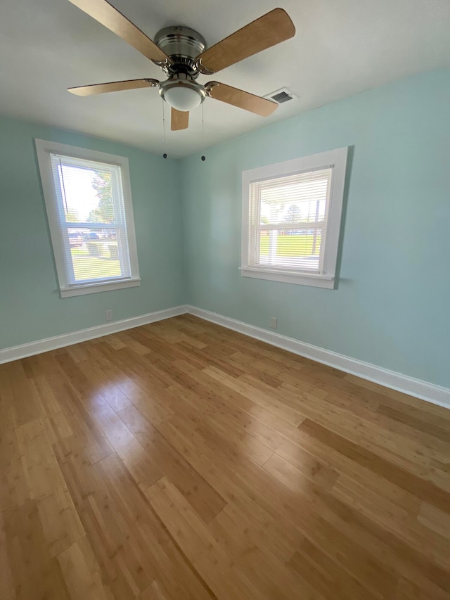 empty room featuring ceiling fan, plenty of natural light, and light hardwood / wood-style flooring