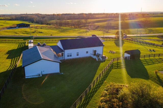 back house at dusk with an outbuilding, a garage, a lawn, and a balcony