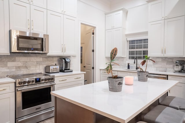 kitchen with decorative backsplash, light countertops, appliances with stainless steel finishes, a sink, and a breakfast bar area