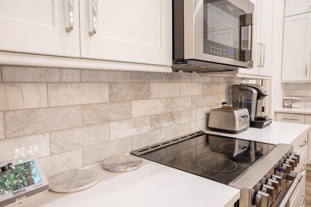 kitchen with a kitchen island, a breakfast bar, tasteful backsplash, white cabinets, and stainless steel appliances