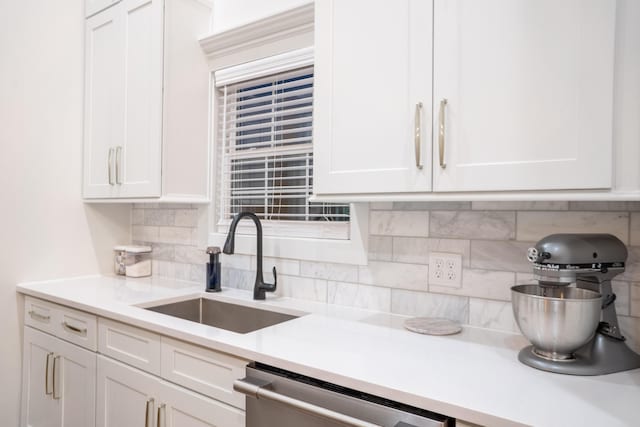 kitchen with white cabinetry, light countertops, backsplash, a sink, and dishwasher