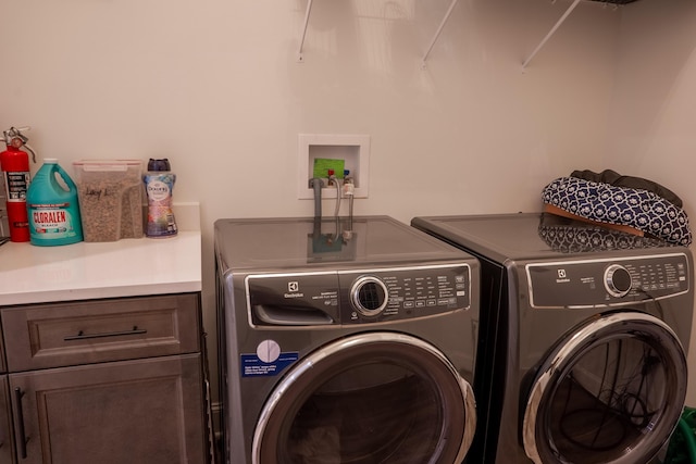washroom featuring independent washer and dryer and cabinet space