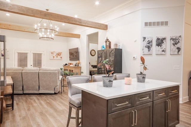 kitchen featuring a notable chandelier, a breakfast bar area, open floor plan, light wood-type flooring, and visible vents