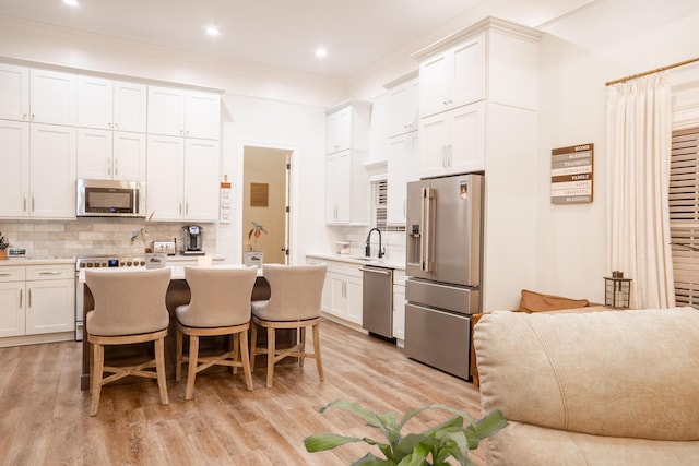 kitchen featuring backsplash, light countertops, stainless steel appliances, and light wood-type flooring