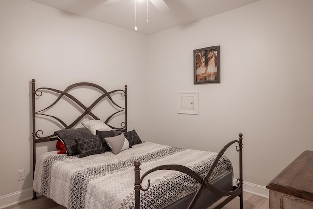 bedroom with a ceiling fan, baseboards, and wood finished floors