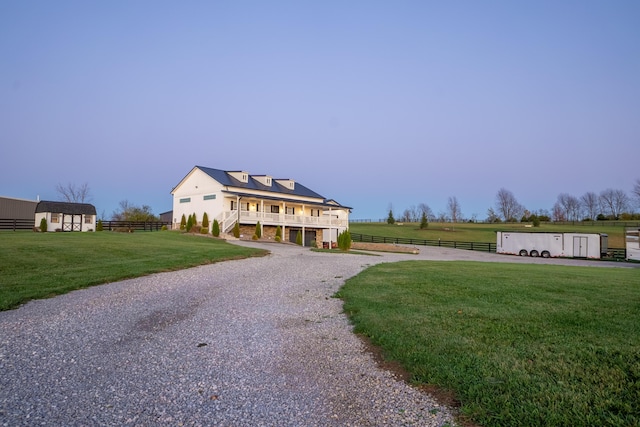 view of front of house with fence, roof mounted solar panels, a front yard, an outbuilding, and curved driveway