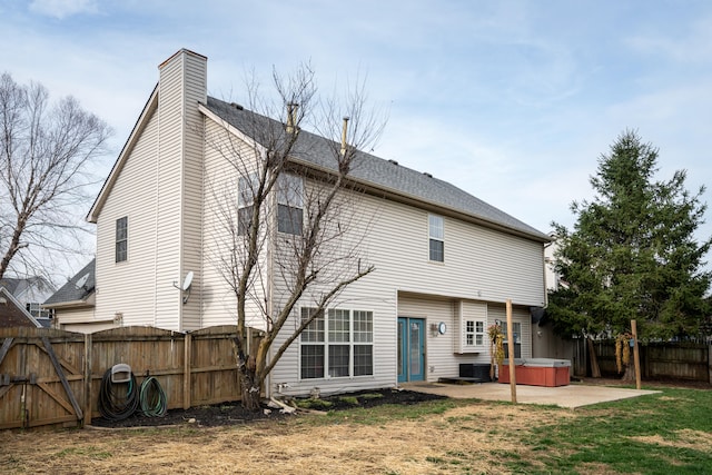 back of house featuring a patio, a hot tub, and a lawn