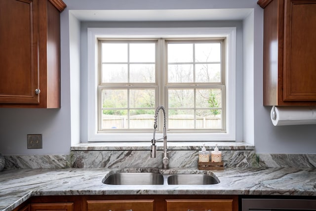 kitchen with light stone countertops, plenty of natural light, and sink