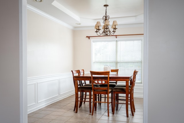 dining space featuring a tray ceiling, light tile patterned flooring, ornamental molding, and an inviting chandelier