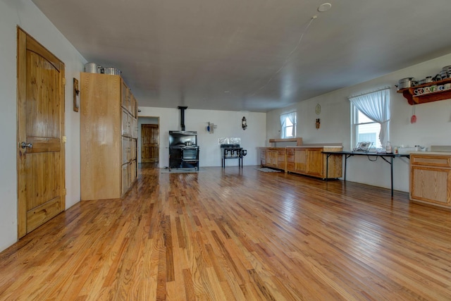 unfurnished living room featuring light wood-type flooring and a wood stove