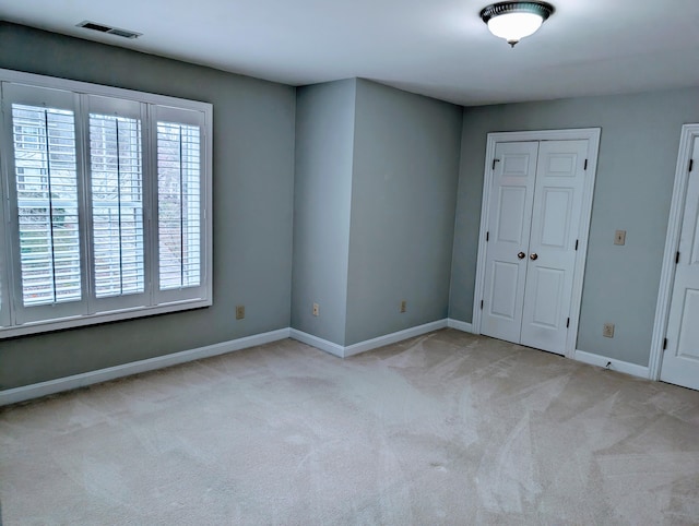 unfurnished bedroom with light colored carpet and a closet