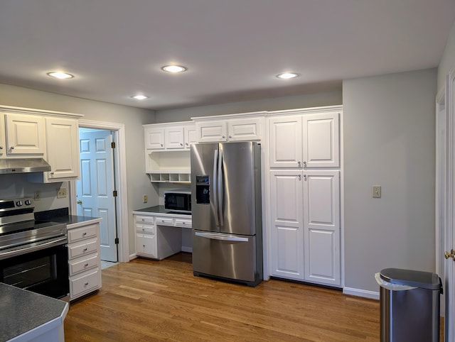 kitchen with white cabinets, appliances with stainless steel finishes, extractor fan, and hardwood / wood-style floors