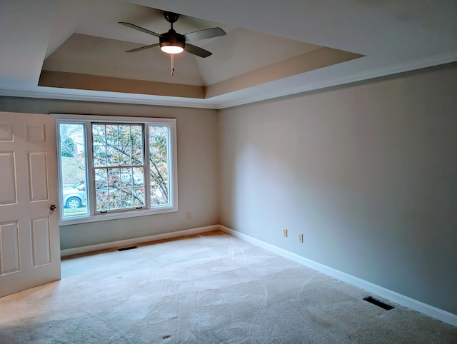 empty room with a tray ceiling, ceiling fan, and light colored carpet