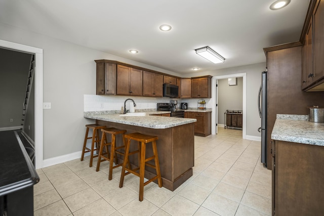 kitchen featuring sink, backsplash, light tile patterned flooring, black range with electric cooktop, and kitchen peninsula