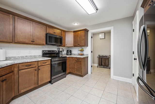 kitchen with light tile patterned floors, decorative backsplash, stainless steel appliances, and light stone countertops