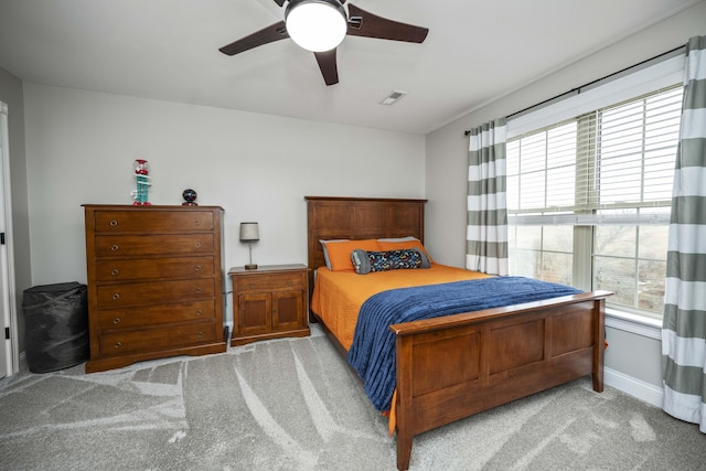 bedroom featuring light carpet, multiple windows, and ceiling fan