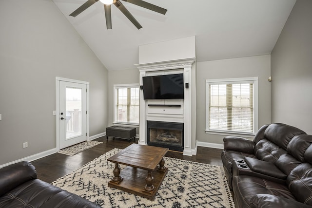 living room with a healthy amount of sunlight, dark hardwood / wood-style flooring, and high vaulted ceiling