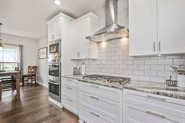 kitchen with white cabinets, wall chimney range hood, tasteful backsplash, dark hardwood / wood-style flooring, and stainless steel appliances