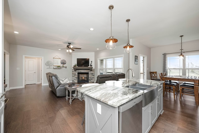 kitchen featuring a kitchen island with sink, pendant lighting, stainless steel dishwasher, and dark hardwood / wood-style floors