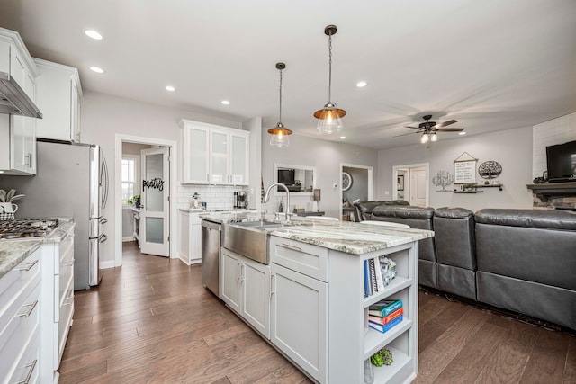 kitchen with stainless steel dishwasher, a kitchen island with sink, sink, pendant lighting, and white cabinetry