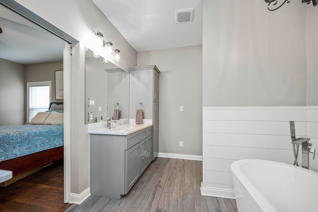 bathroom with hardwood / wood-style flooring, vanity, and a tub