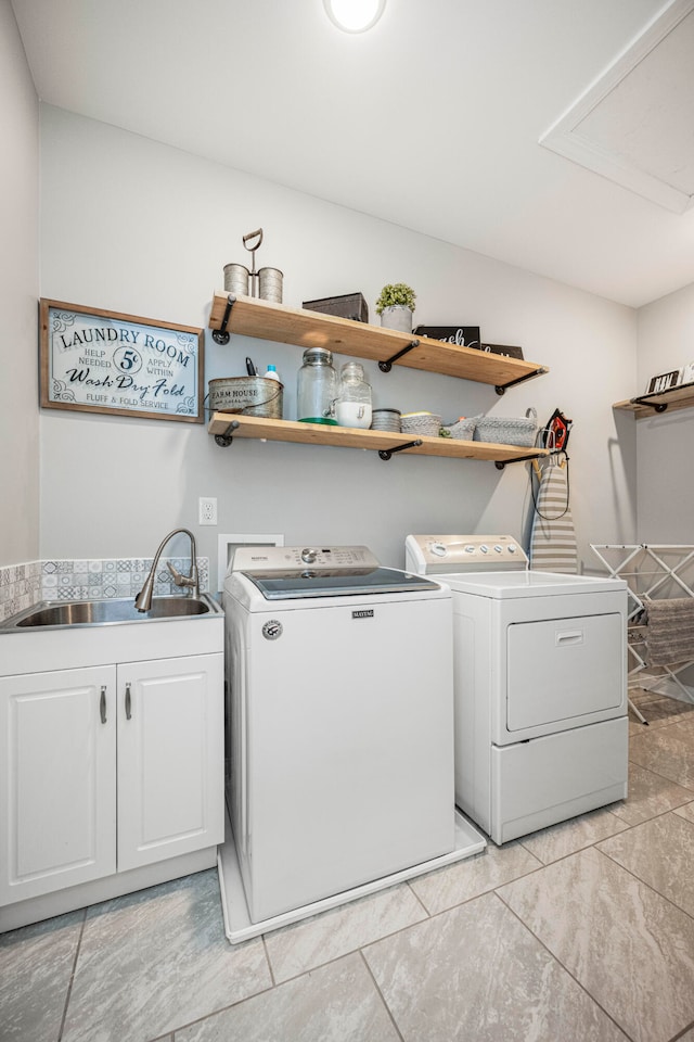 clothes washing area featuring separate washer and dryer, sink, and cabinets