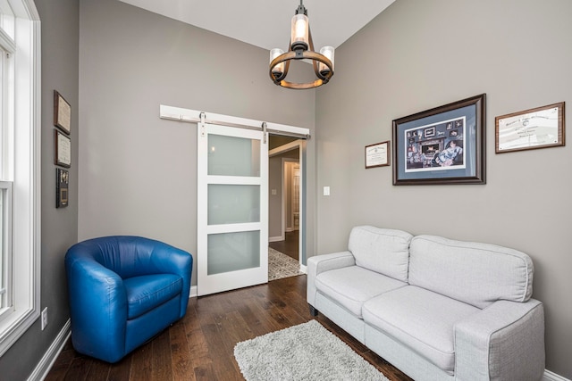 living room featuring a barn door, dark hardwood / wood-style flooring, high vaulted ceiling, and an inviting chandelier