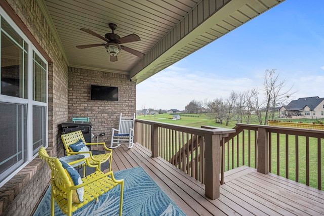 wooden terrace featuring ceiling fan and a yard