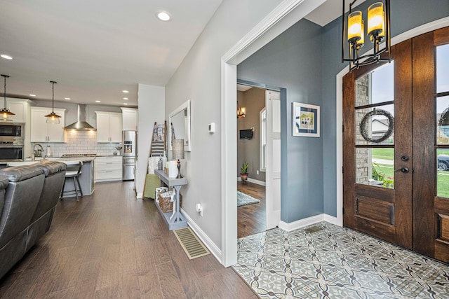 foyer with french doors, light wood-type flooring, an inviting chandelier, and sink