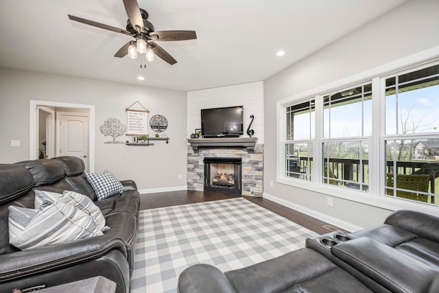 living room with a stone fireplace, ceiling fan, and dark hardwood / wood-style floors