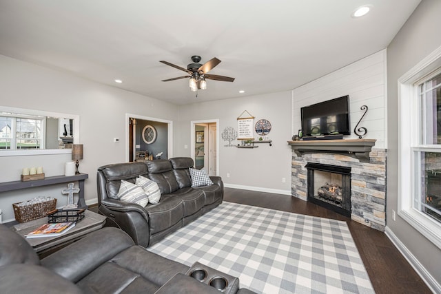 living room featuring ceiling fan, a fireplace, and dark wood-type flooring