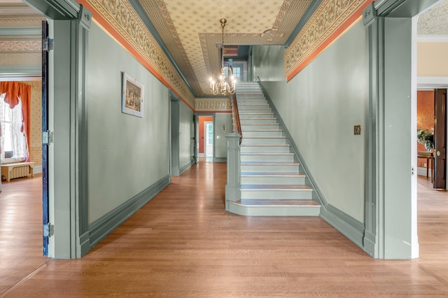 corridor with radiator, an inviting chandelier, a barn door, light hardwood / wood-style flooring, and ornamental molding