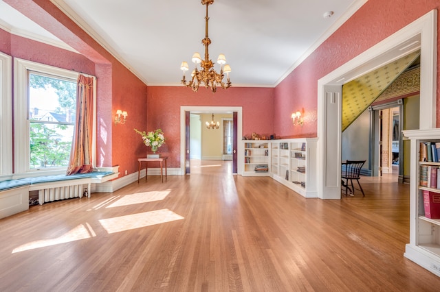 interior space featuring radiator heating unit, hardwood / wood-style flooring, crown molding, and a notable chandelier