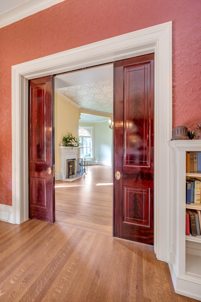 hallway featuring light hardwood / wood-style flooring, an inviting chandelier, a textured ceiling, and ornamental molding