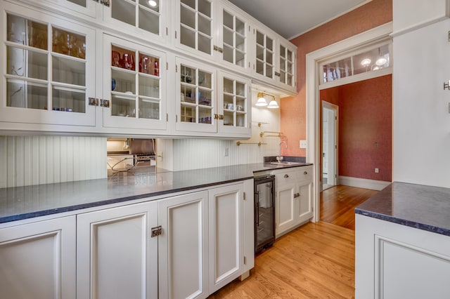 kitchen with light hardwood / wood-style floors, white cabinetry, sink, and beverage cooler