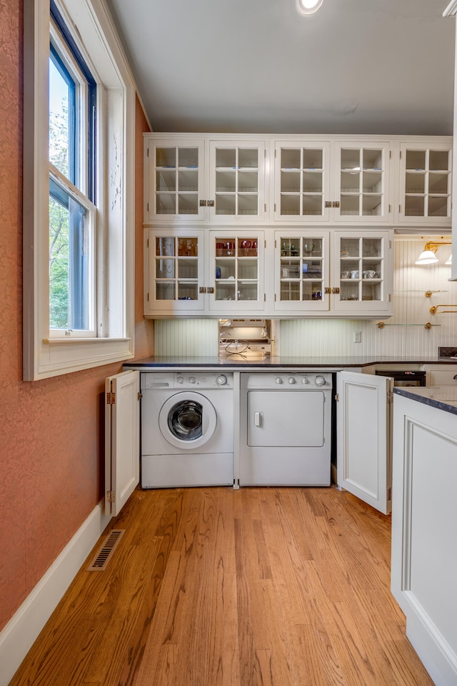 washroom featuring cabinets, light hardwood / wood-style floors, and washing machine and clothes dryer