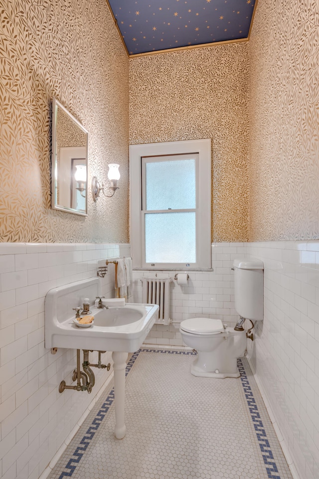 bathroom with crown molding, toilet, radiator heating unit, and tile walls