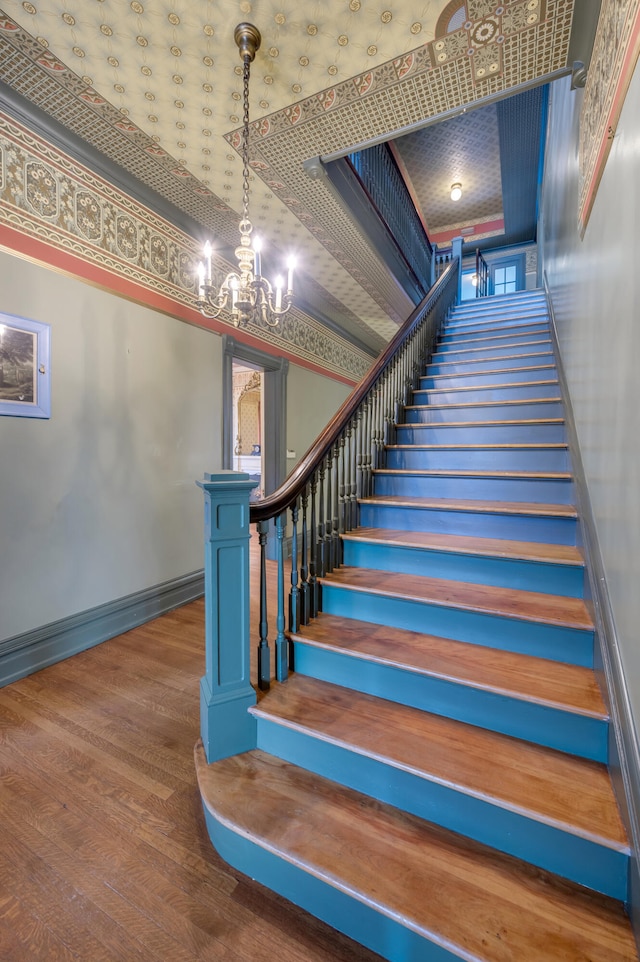 staircase featuring wood-type flooring, a towering ceiling, and an inviting chandelier