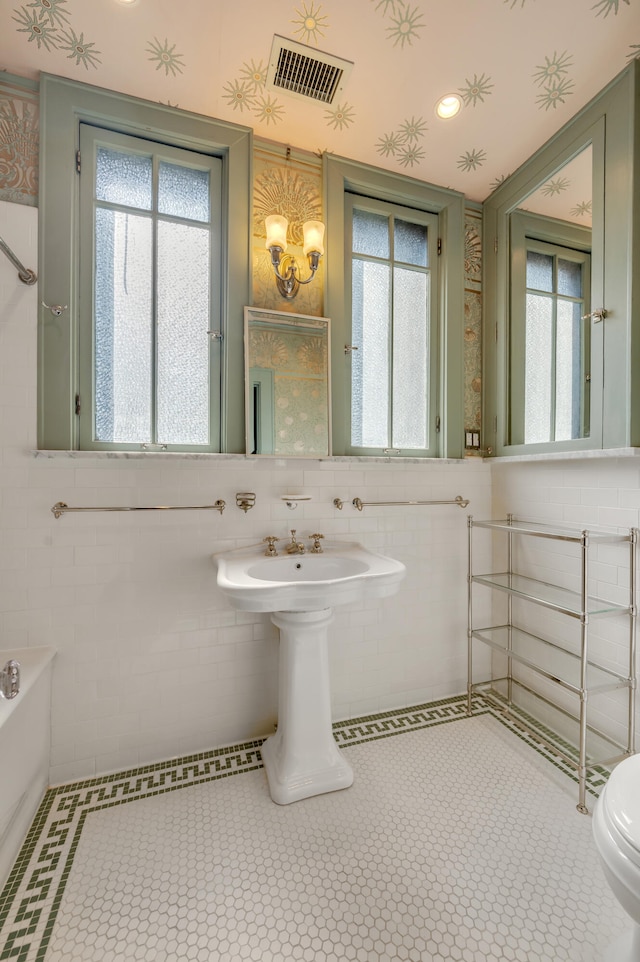 bathroom featuring a healthy amount of sunlight, toilet, and tile walls