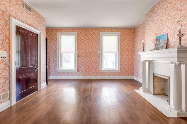 unfurnished living room with a fireplace, wood-type flooring, and a healthy amount of sunlight