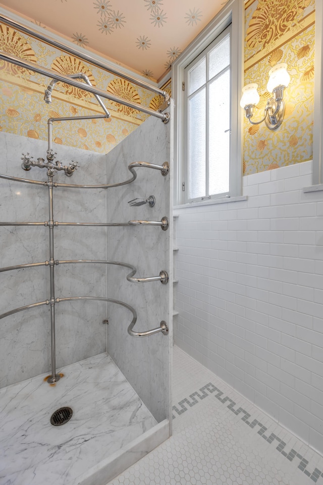 bathroom featuring tile patterned floors, a tile shower, and tile walls