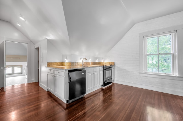 kitchen featuring lofted ceiling, white cabinets, black fridge, light stone countertops, and dark hardwood / wood-style flooring