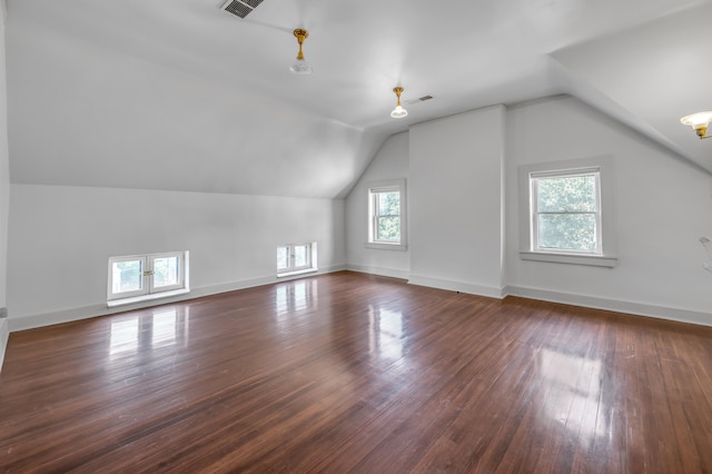 additional living space with dark hardwood / wood-style flooring, vaulted ceiling, and a notable chandelier