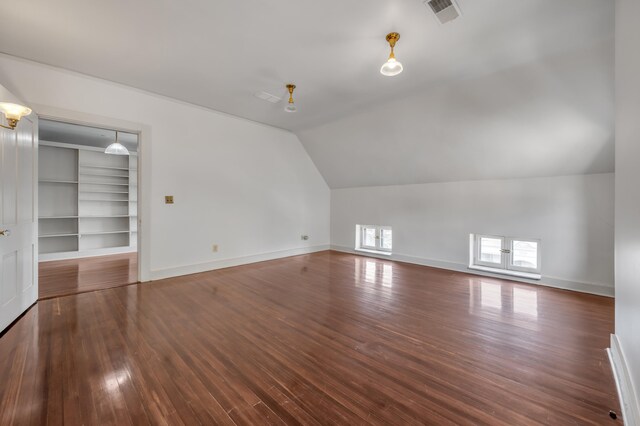 bonus room with built in shelves, dark hardwood / wood-style flooring, and lofted ceiling